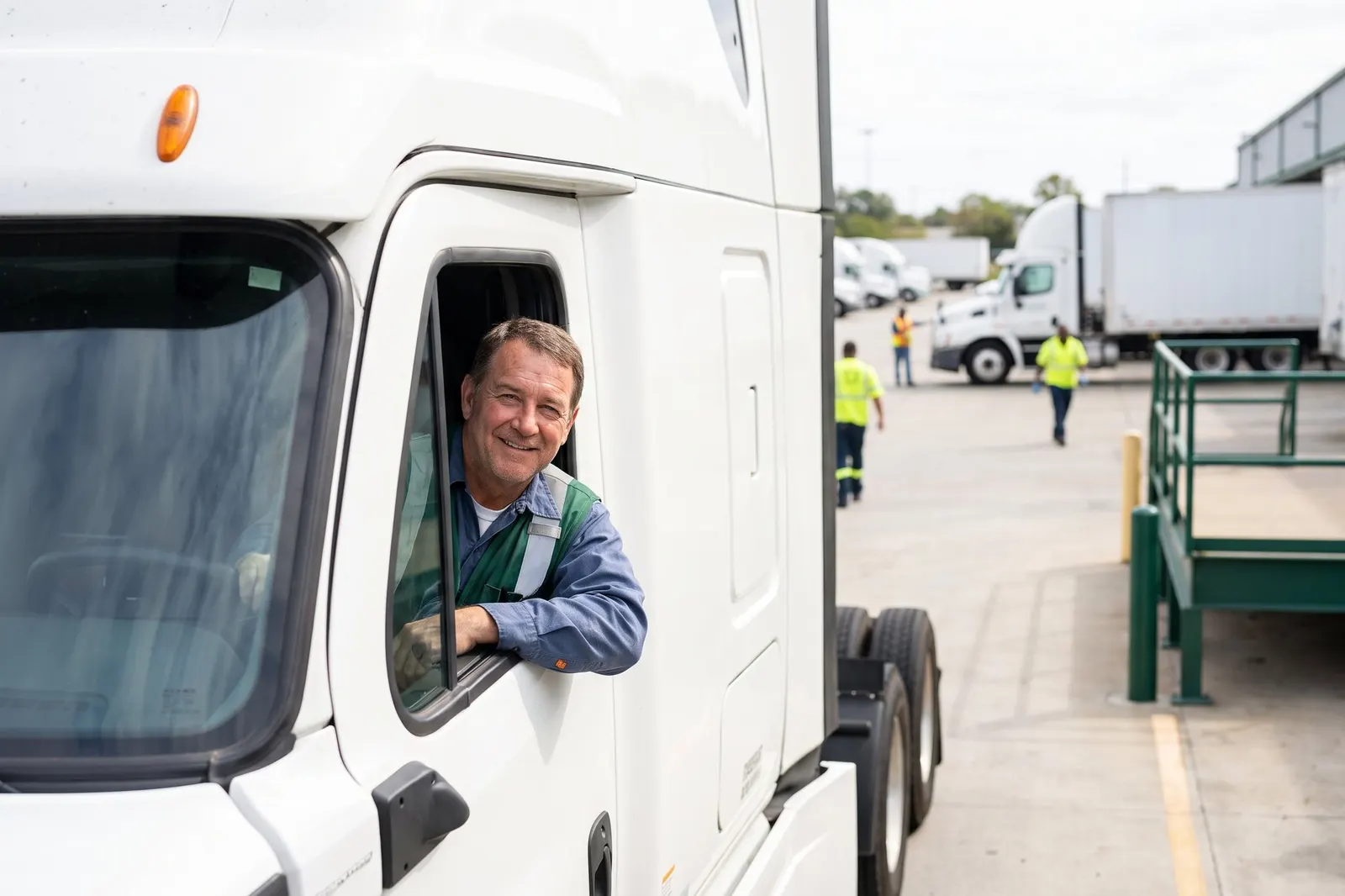 A smiling truck driver at the window of his cab