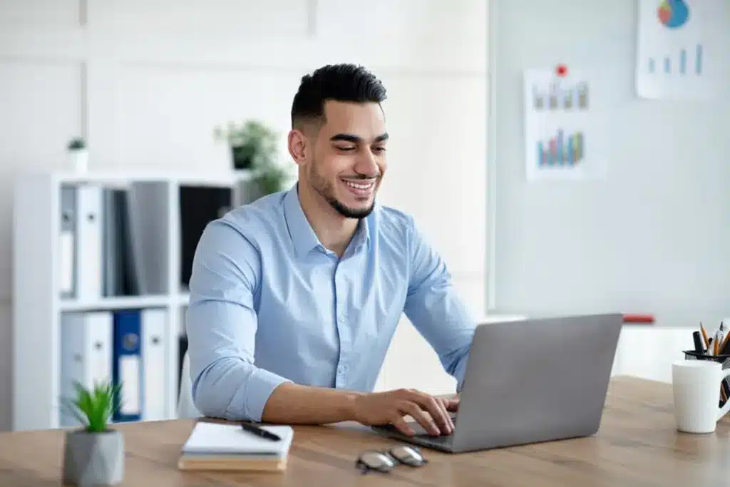 Man in an office setting at a desk typing on a laptop