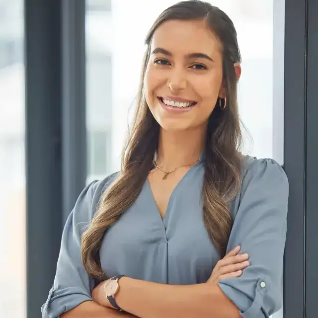 Professional businesswoman in blue shirt standing confidently by office door