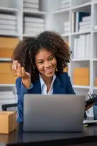 Smiling African American businesswoman celebrating success while working on laptop in startup office