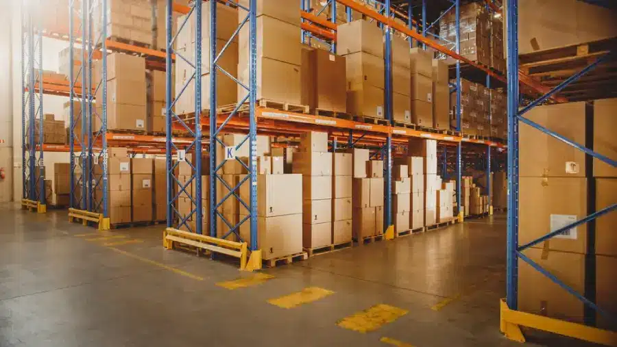 Large warehouse with blue metal shelving storing cardboard boxes on wooden pallets