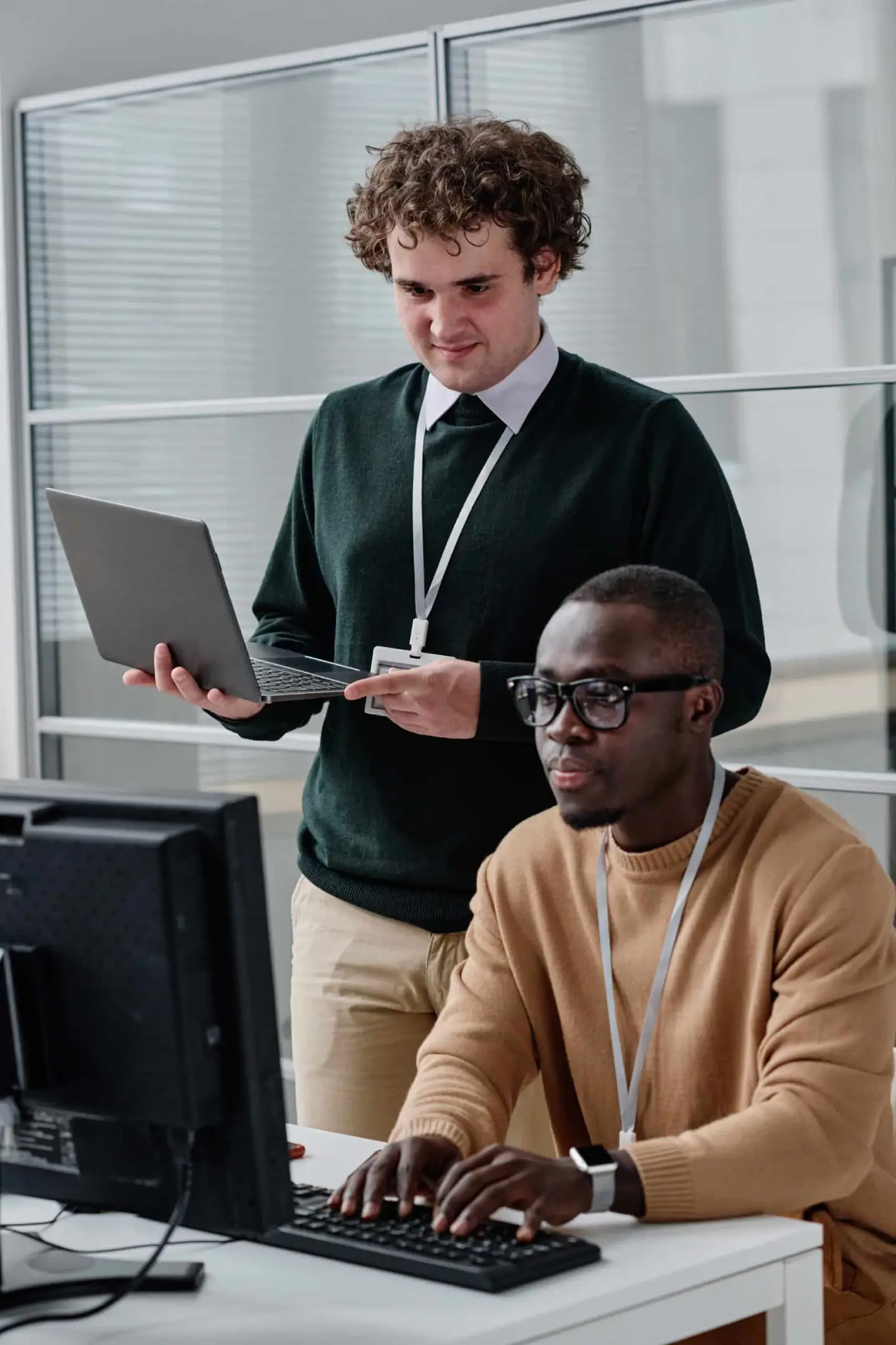 Two software developers collaborating on computer programming in modern office workspace