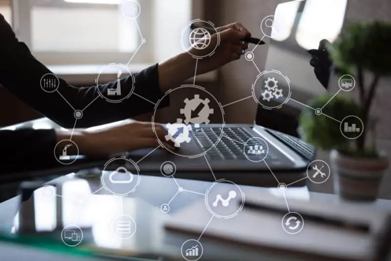 Business professional using laptop with digital automation and workflow technology icons overlay