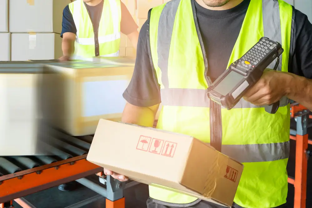 Warehouse workers in safety vests scanning packages with handheld barcode scanner