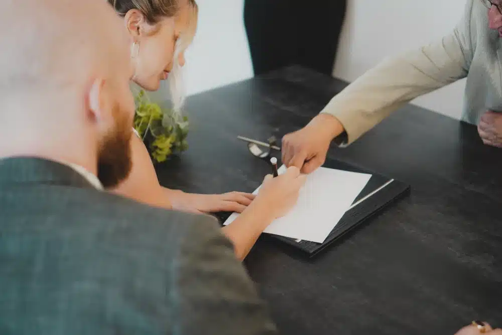 woman signing paper while others watch