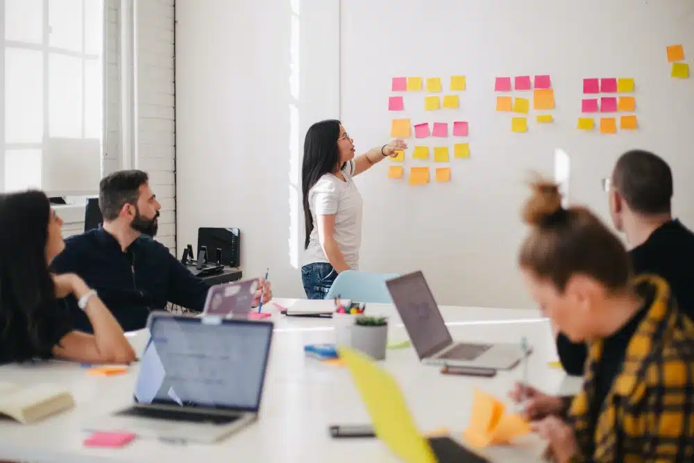 woman standing in front of conference room with colored sticky notes on the wall