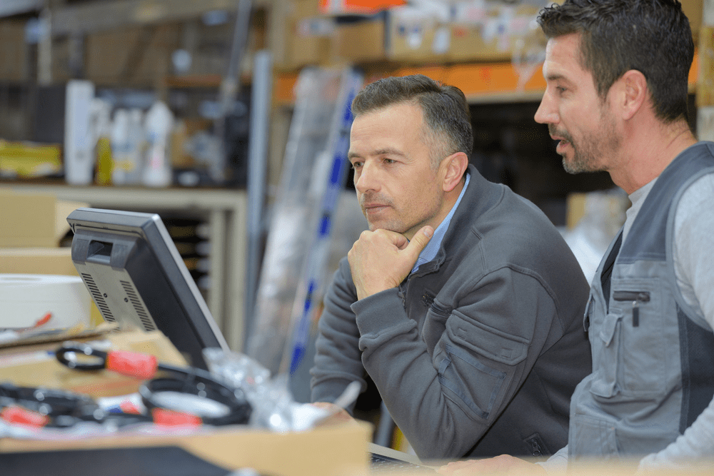 two warehouse workers looking at a computer screen