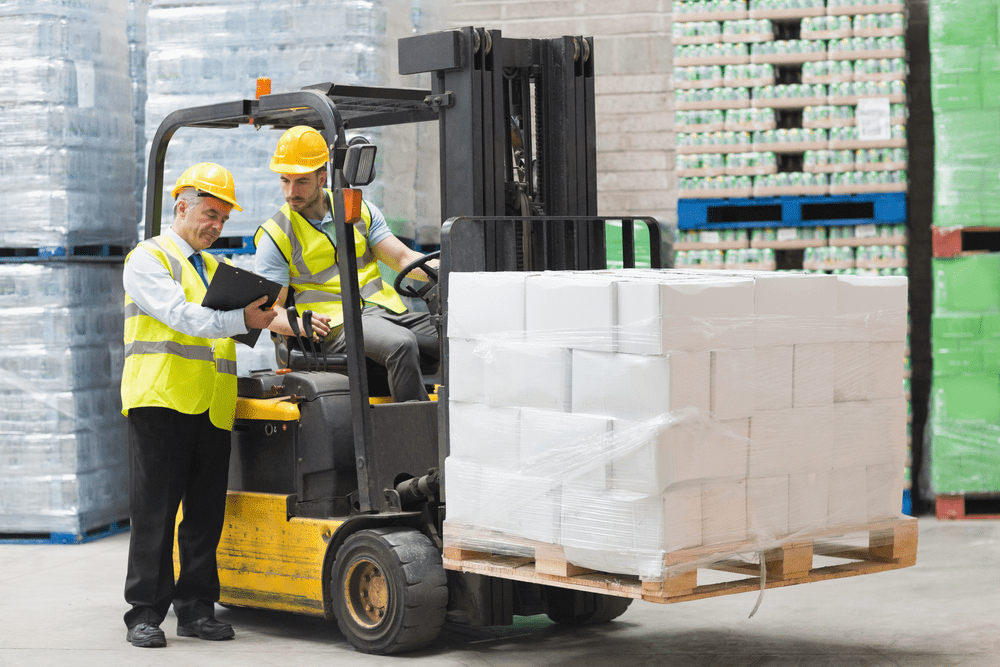 warehouse worker on a forklift talking to another worker holding a clipboard