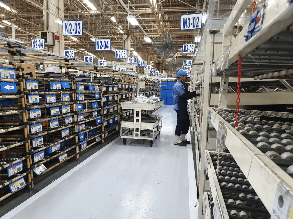 warehouse worker picking orders in a warehouse aisle with bin locations marked by signs