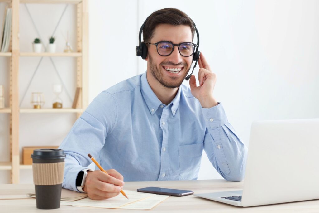 man in front of a laptop speaking with a customer on his headset