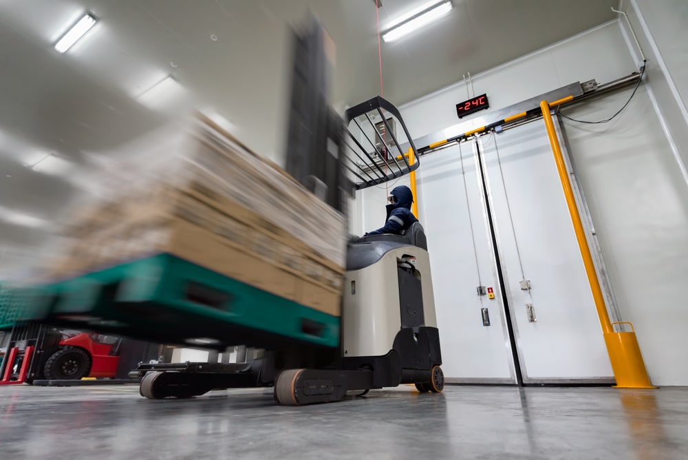 Worker,Stand-on,Stacker,Truck,Used,To,Lift,And,Move,The forklift in cold storage warehouse