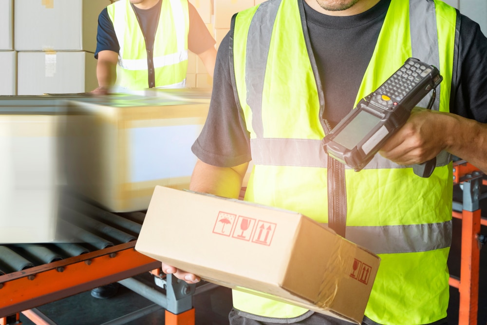 Worker,Holding,Barcode,Scanner,With,Scanning,On,Package,Box,,Manufacturing warehouse worker scanning a box with an RF scanner