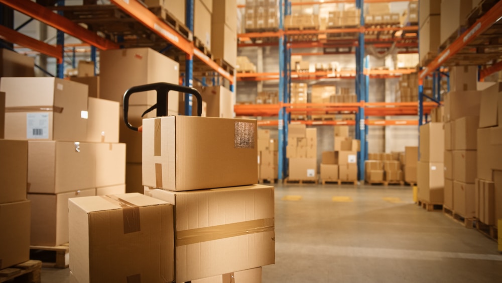 Big,Retail,Warehouse,Full,Of,Shelves,With,Goods,Stored,On stack of boxes on a pallet truck in a warehouse