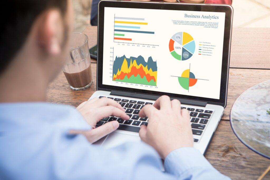 man at a desk reviewing business analytics charts and graphs on his laptop