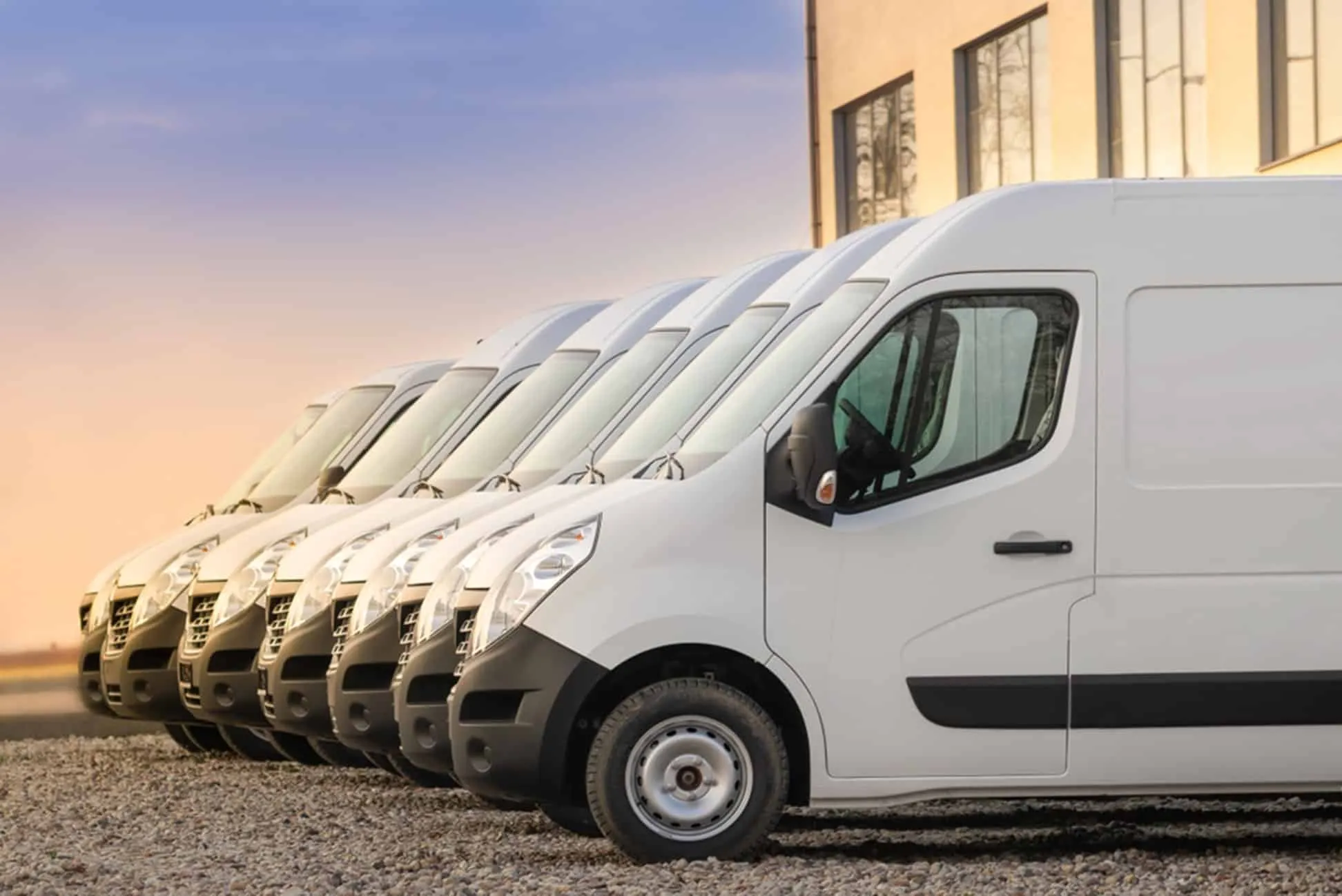 Fleet of white commercial delivery vans lined up at business distribution facility